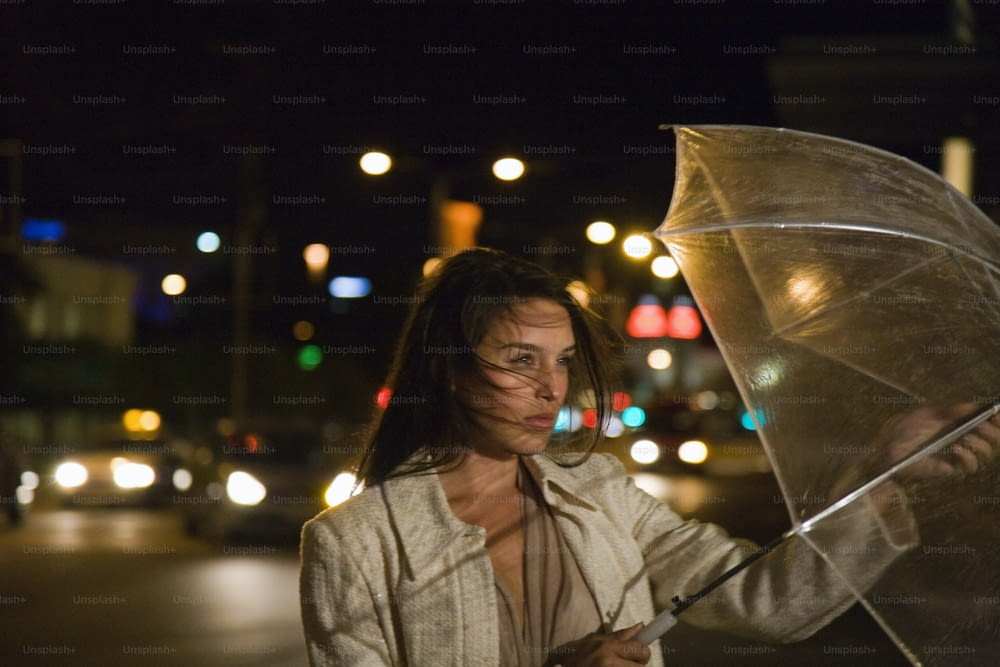 a woman holding an umbrella on a city street at night