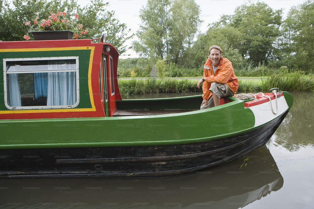 a woman sitting on the side of a green and red boat