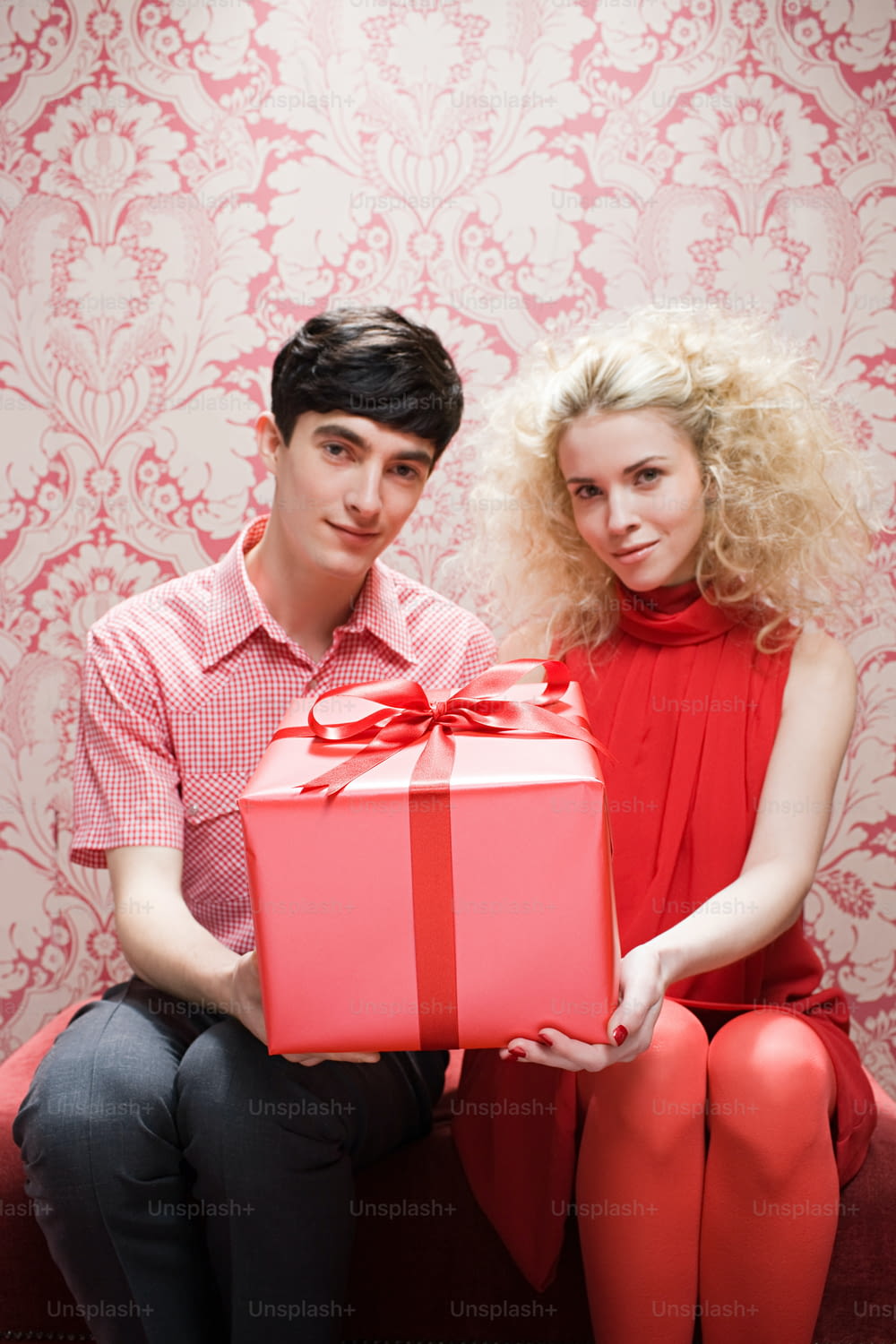 a man and a woman sitting on a couch holding a present