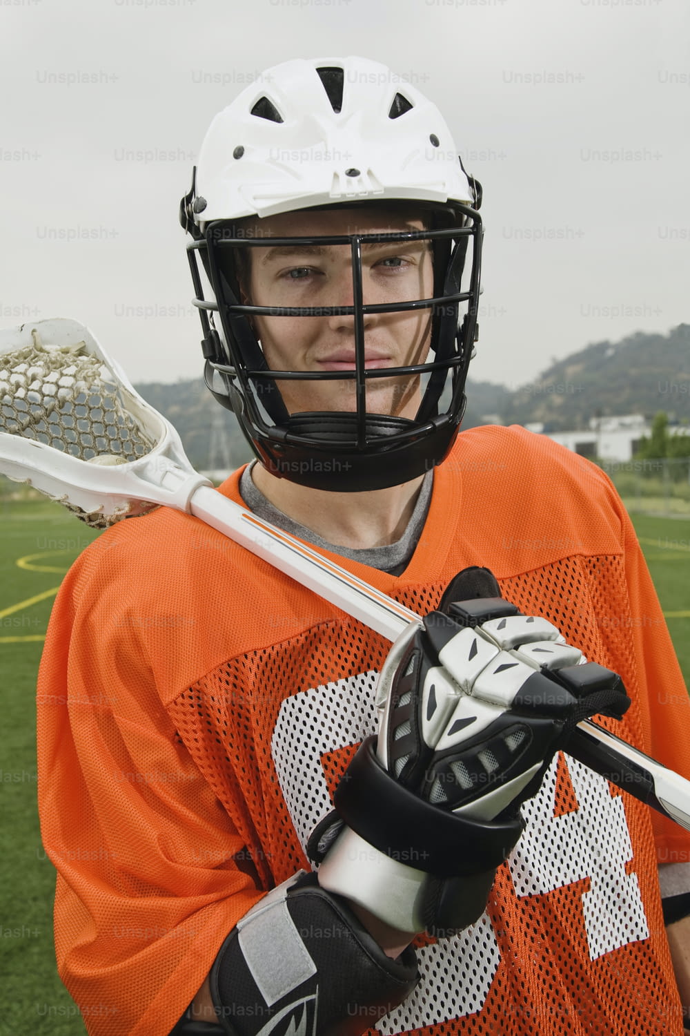 a man in an orange jersey holding a lacrosse stick