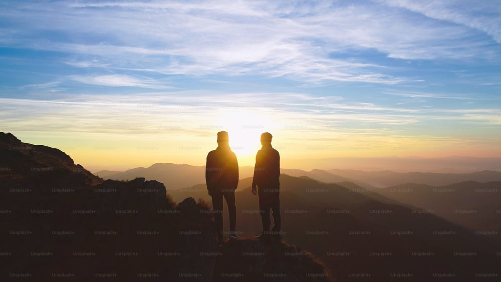 Le couple debout sur la montagne sur le magnifique fond de lever du soleil