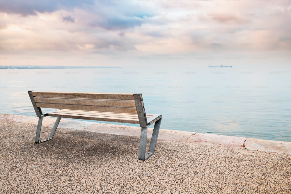 穏やかな海辺の堤防に孤独なロマンチックなベンチがある展望台