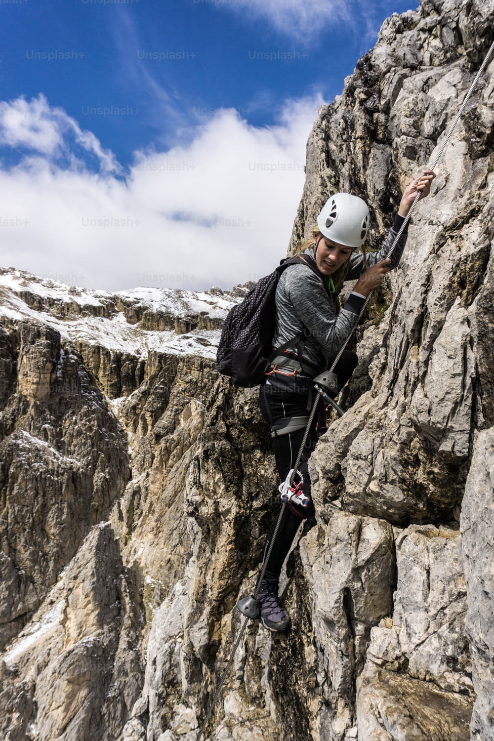 Attractive blond female climber on a steep and exposed Via Ferrata in the South Tyrol