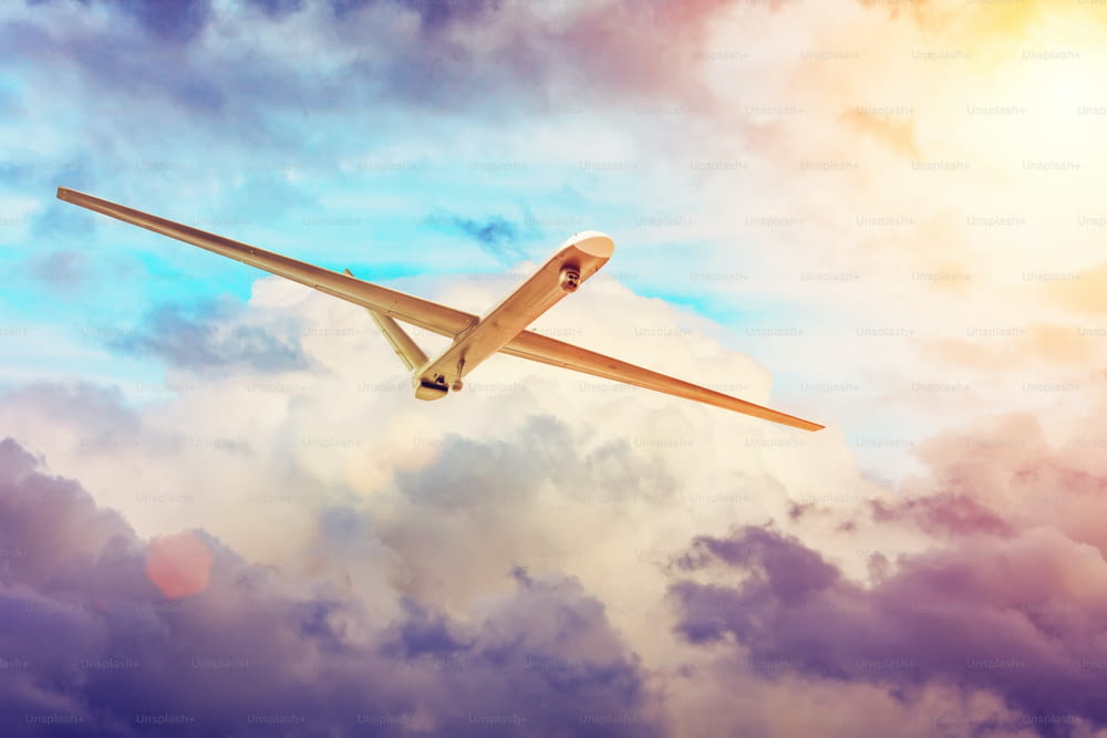 Drone de avião militar não tripulado voa o céu nublado ao pôr do sol