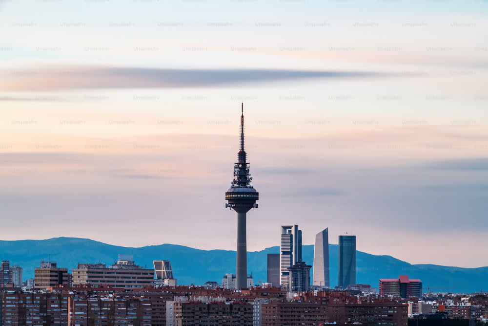 Skyline de Madrid ao entardecer visto do Cerro del Tio Pio, com a Torre de TV e os arranha-céus ao longo de Castellana a serem reconhecidos. Longa exposição.