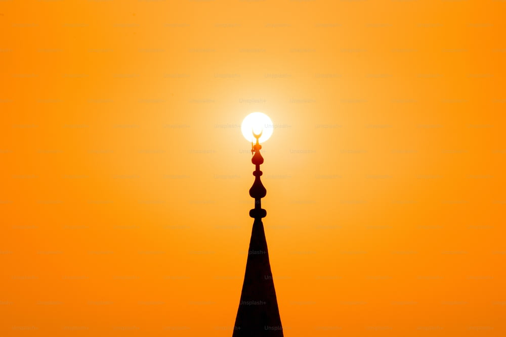 Coucher de soleil rouge avec soleil et silhouette du minaret de la mosquée