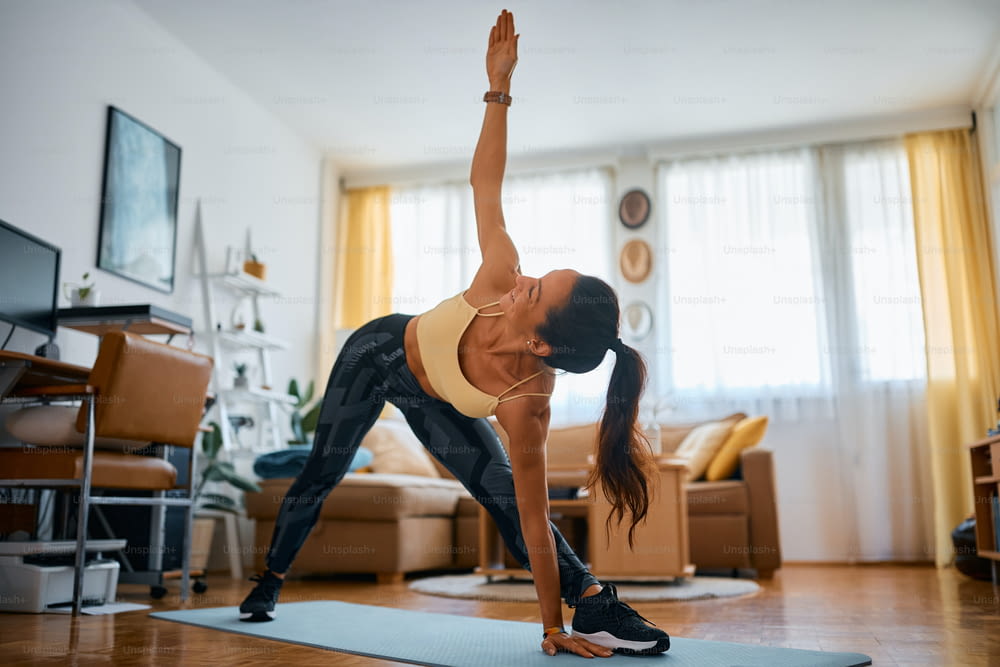 Happy sportswoman doing stretching exercise during home workout.