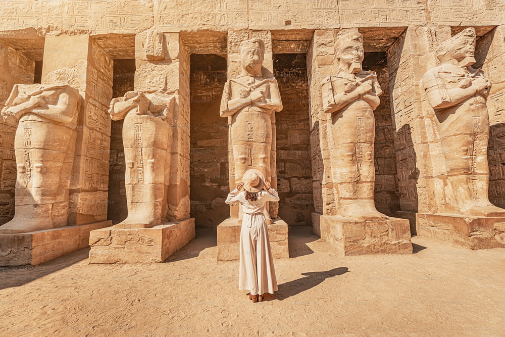 Una feliz turista vestida se interesa por la egiptología y la arqueología y tiene una experiencia de viaje en el Templo de Karnak en Luxor.