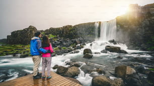 Couple travelers travel to Oxararfoss waterfall in Thingvellir National Park, Iceland. Oxararfoss waterfall is famous waterfall attracting tourist to visit Thingvellir.