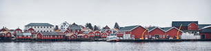 Panorama of Reine fishing village on Lofoten islands with red rorbu houses, pier and fishing boats in winter. Norway