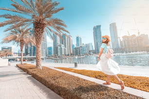 Glückliches asiatisches Mädchen auf einer Promenade im Viertel Dubai Marina. Reisen und Lebensstil in Vereinigte Arabische Emirate