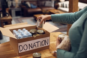 Gros plan d’une femme préparant une boîte de dons pour une banque alimentaire caritative.