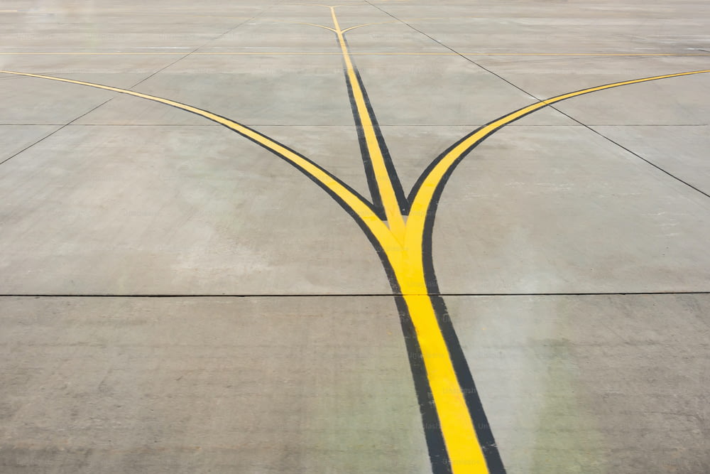 Fourche de bandes directionnelles jaunes en gros plan sur une piste d’aérodrome
