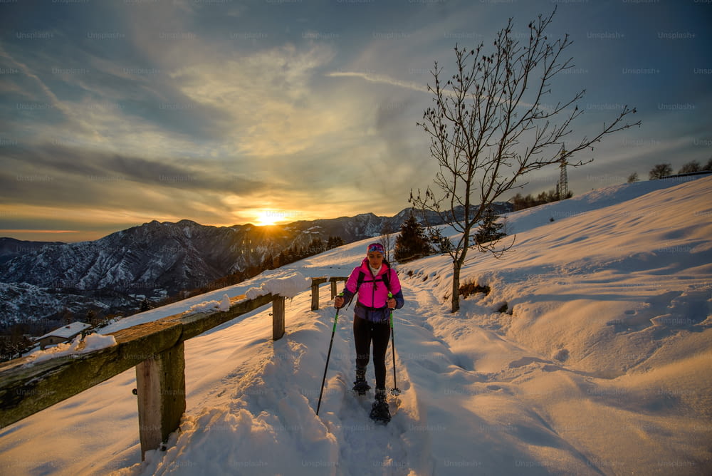 Young woman alone on snowshoe hike on beautiful sunset day