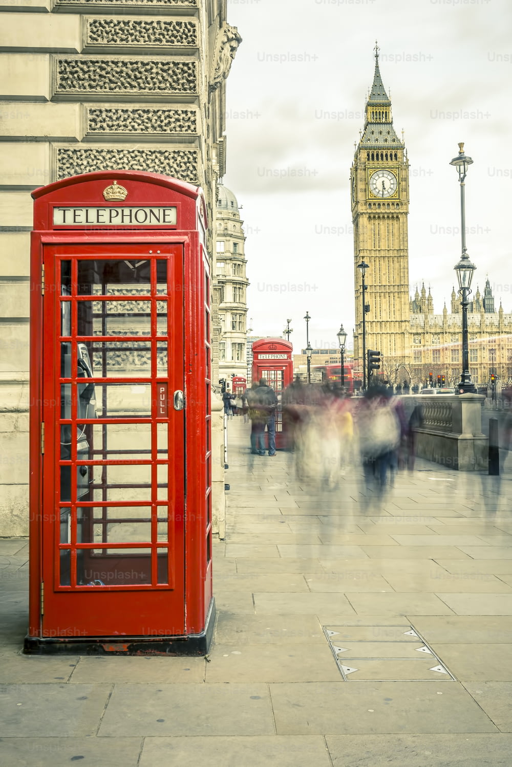 The iconic british old red telephone box with the Big Ben at background in the center of London