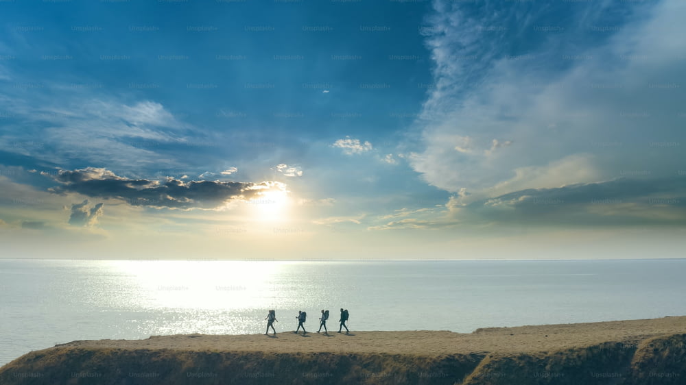 El grupo de cuatro personas caminando hacia el borde de la montaña cerca del mar