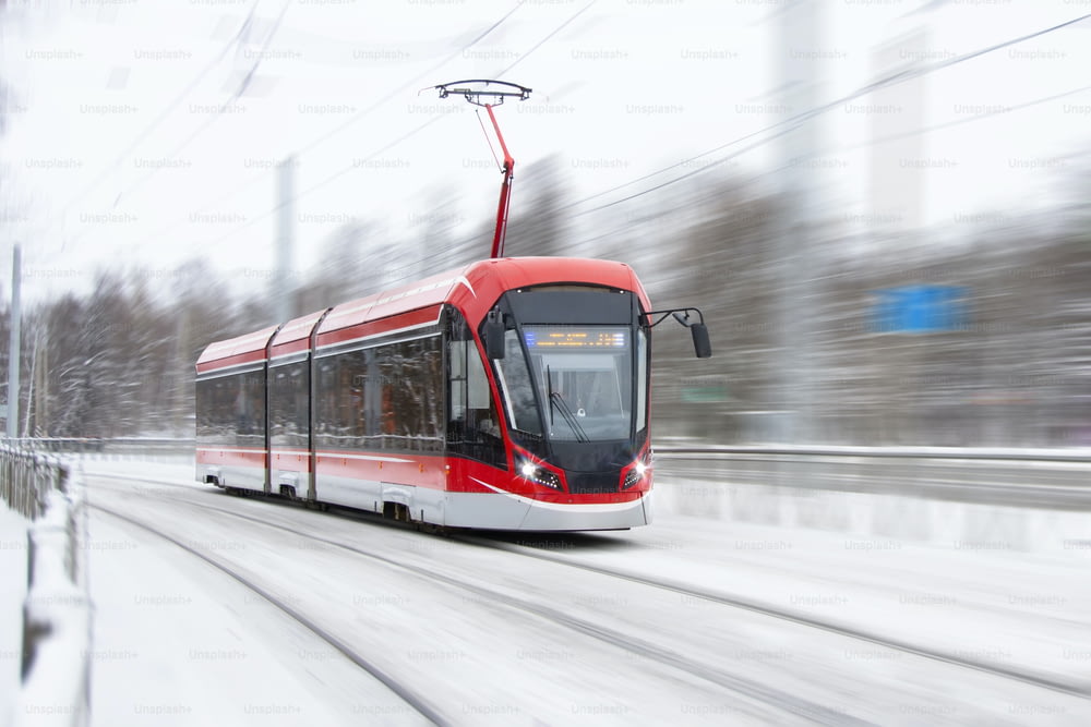 El tranvía pasa rápidamente en una curva de un parque urbano cubierto de nieve