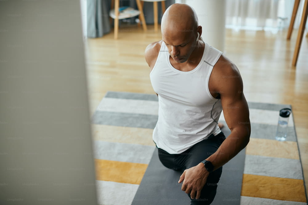 African American athletic man stretching while having sports training at home. Copy space.