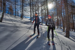 Two girls in the woods with mountaineering skis ascend.