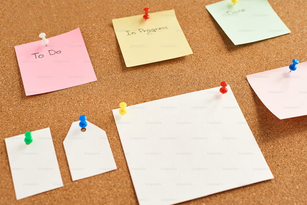 Appunti di carta colorati con le parole "Da fare", "In corso" e "Fatto" appuntati su una lavagna di sughero