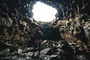 Woman traveler explore lava tunnel in Iceland. Raufarholshellir is a beautiful hidden world of cave. It is one of the longest and best-known lava tubes in Iceland, Europe for incredible adventure.