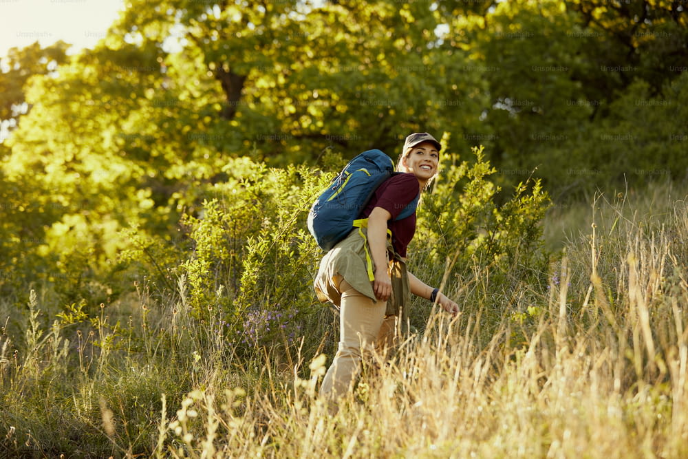 Vue en contre-plongée d’une femme heureuse avec un sac à dos en randonnée tout en passant une journée dans la nature.