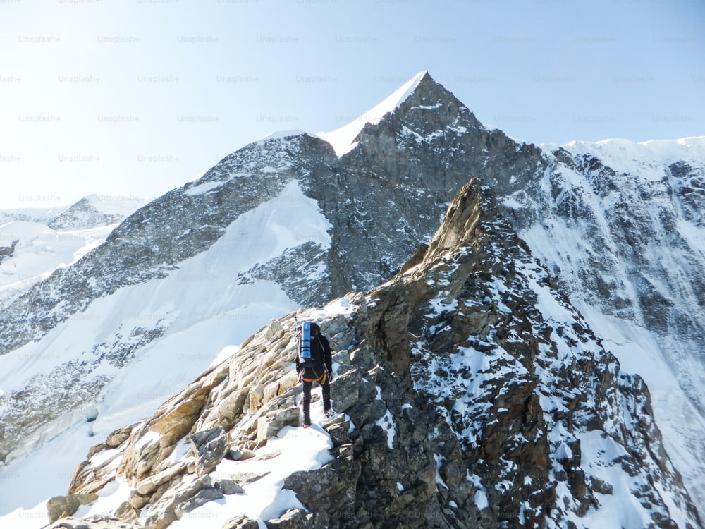 산악 가이드가 높은 알프스 봉우리 정상을 향해 향하며 스위스 인테라켄 근처의 노출된 바위 능선을 오르고 있다.