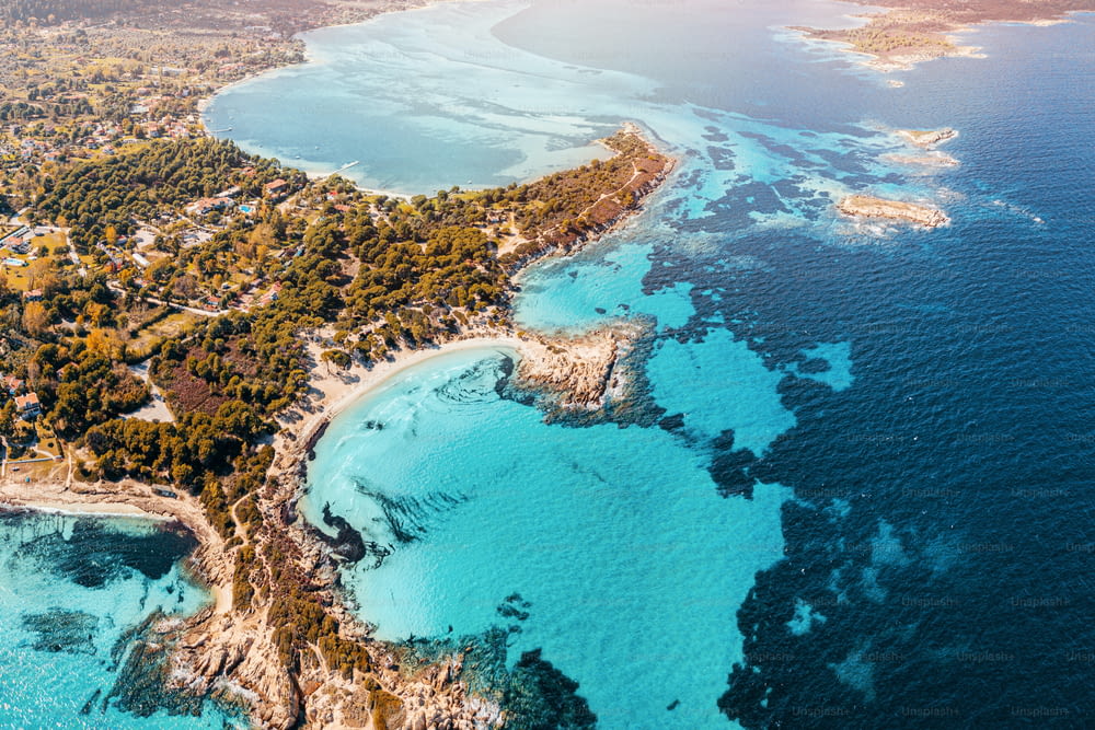 Aerial view of the paradise seashore with various shades of turquoise water. Coral reefs at depth and secluded sandy beaches in the resort village of Vourvourou in Greece