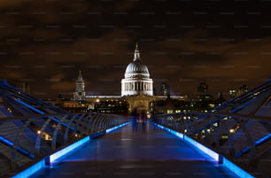 St. Paul's Cathedral and the Millenium footbridge illuminated at night in London, United Kingdom.