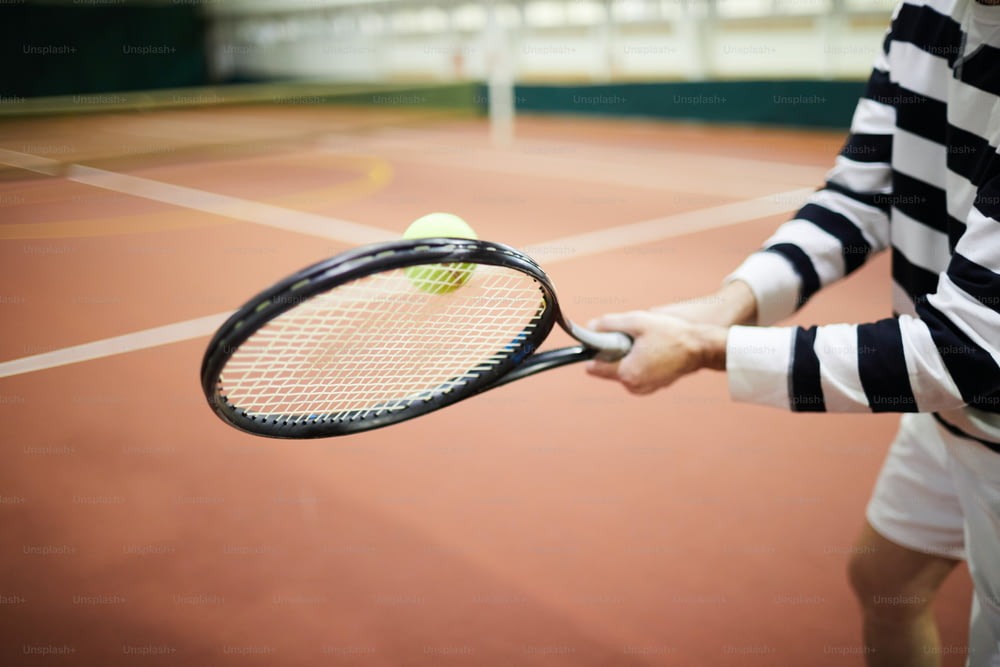 경기장에서 성공적인 경기 중 라켓으로 테니스 공을 치는 활동적인 테니스 선수