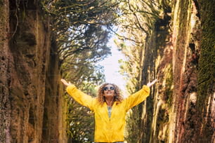 Viaje y felicidad personas concepto de estilo de vida libre con una joven mujer adulta alegre y hermosa disfrutando del bosque y la naturaleza con chaqueta amarilla