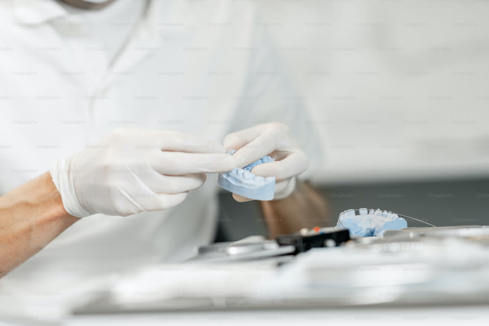 Dental technician working with a model of teeth trying on a brace system for orthodontic treatment at the laboratory. Close-up. High quality photo