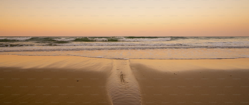 Bella spiaggia di sabbia come il paradiso posto per le vacanze estive. lato oceano e onde durante un tramonto colorato sullo sfondo. nessuno lì