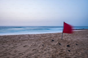 Einsamer Strand ohne Körper am frühen Morgen mit Langzeitbelichtung. Sand und blaues Wasser des Ozeans. Fuerteventura Dünen Corrralejo Ort für Ihr nächstes Urlaubsziel. Rote Gefahrenflagge