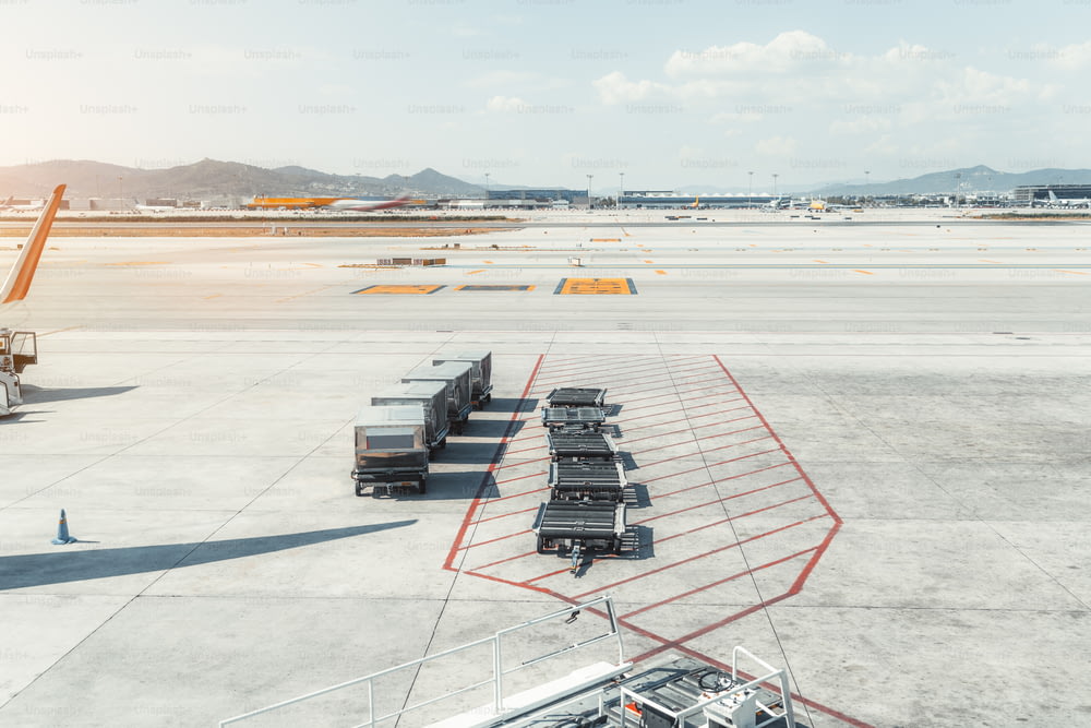 바르셀로나의 현대적인 공항 터미널 El Prat의 탑승 구역에 있는 기계의 모습, 식사가 담긴 컨테이너 4개와 빈 연결된 수하물 카트, 배경에 이륙 필드