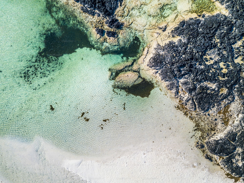 Vue aérienne verticale de la plage de sable blanc du lagon blanc et de l’eau claire de la tourquoise - station balnéaire belle destination de vacances d’été avec océan et rochers - concept de paradis et de détente avec la nature