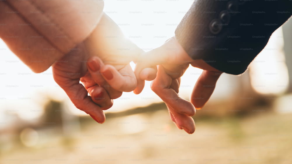 Nahaufnahme zweier Händchenhaltender Liebender bei Sonnenuntergang - Vertrauen, Liebe, Beziehung und Unterstützungskonzept