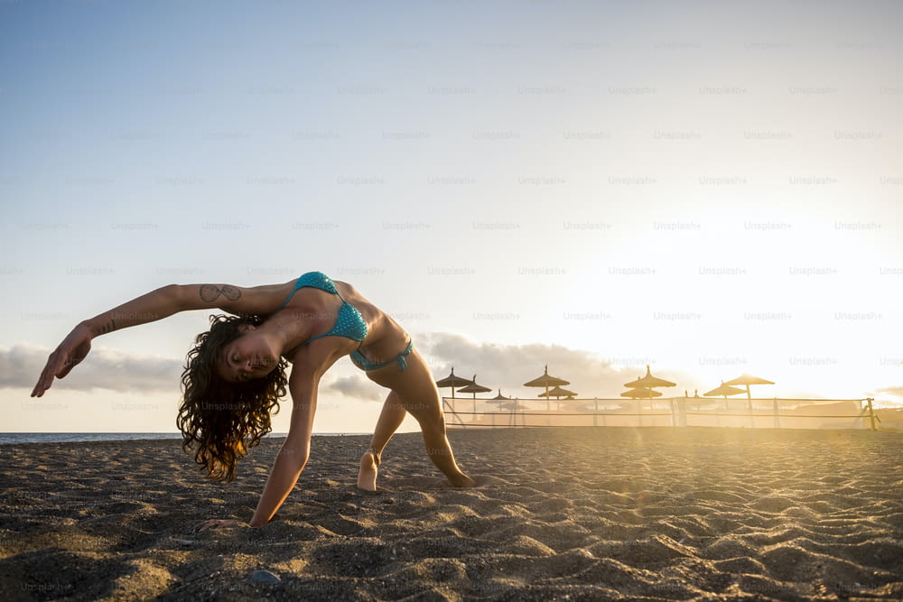 Entrenamiento de fitness de yoga y pilates en la playa para una morena atractiva haciendo ejercicios - luz dorada del atardecer en el fondo - estilo de vida saludable para los jóvenes millennials - concepto de vida en forma al aire libre