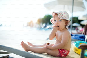 여름 휴가에 해변에 앉아 있는 귀여운 작은 유아 소녀. 공간을 복사합니다.