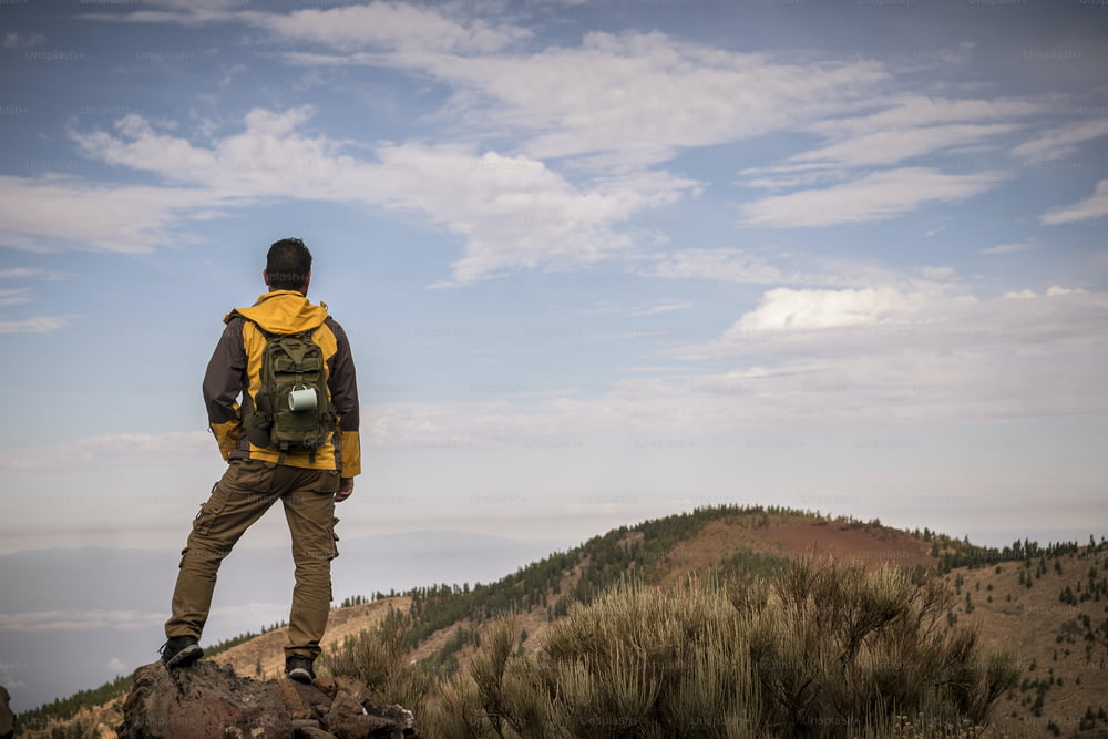 Einsamer Mann im Trekking-Abenteuer entdecken Aktivität am Berg mit Rucksack - Wanderer schaut die Landschaft und genießt die wilde unentdeckte Natur - schöne Umgebung für alternativen Urlaub