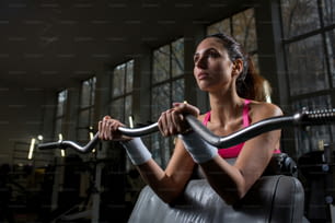Pretty sportswoman weightlifting in contemporary sports club during workout
