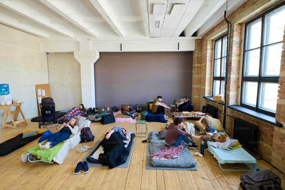 Plusieurs lieux de couchage avec des sans-abri temporaires se reposant et communiquant entre eux dans une chambre spacieuse
