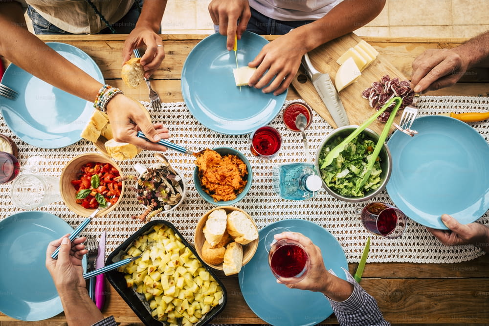 Les gens mangent ensemble dans une fête d’amitié ou de famille avec une table pleine de nourriture vue du haut vertical - amis et ont un concept amusant - couleurs et fond avec table en bois