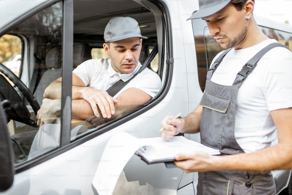 Delivery company employees in uniform delivering goods by cargo van vehicle, mover with a car driver checking delivery list