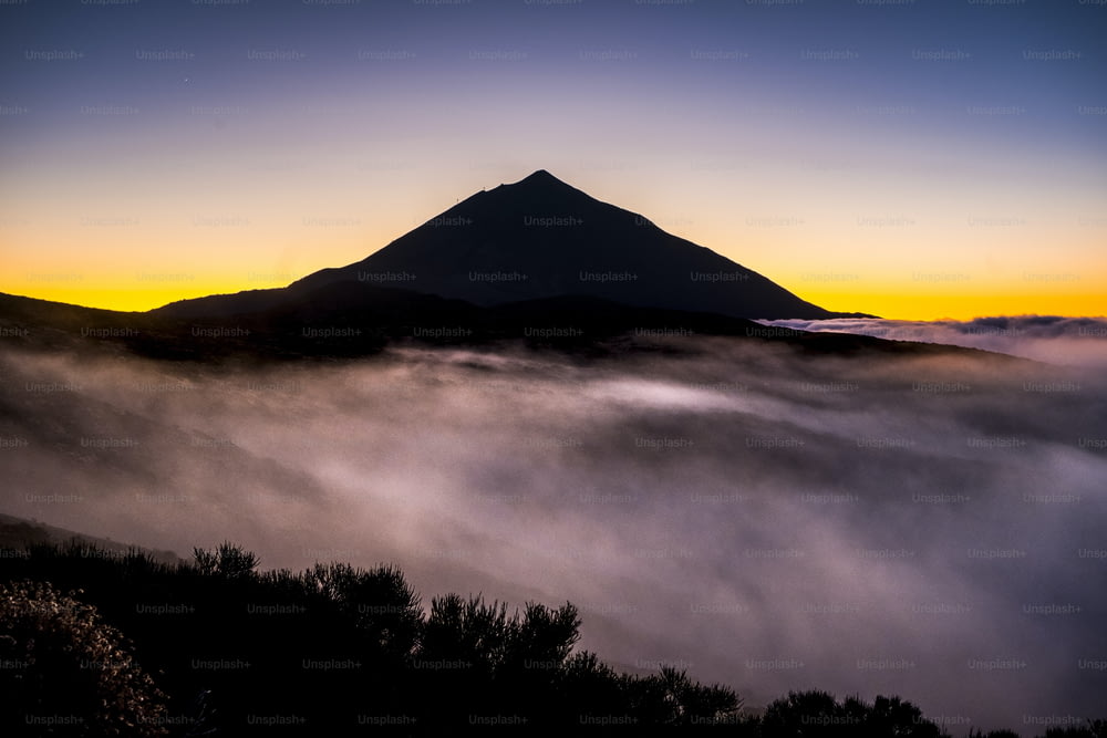 Beautiful el teide tenerife vulcan landscape with  high top and clouds in the ground like mist fog - timeless and national park scenic outdoor place - coloured backgorund and wild nature