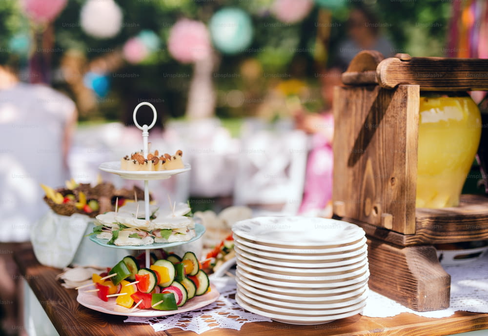 Food on table on kids birthday party outdoors in garden in summer, celebration concept.