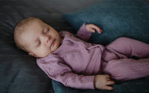 a Portrait of newborn baby girl, sleeping an lying on sofa indoors at home.