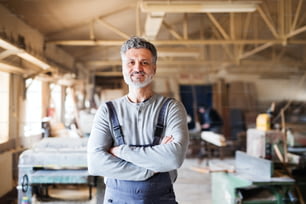 Portrait of a mature man worker in the carpentry workshop, arms crossed.