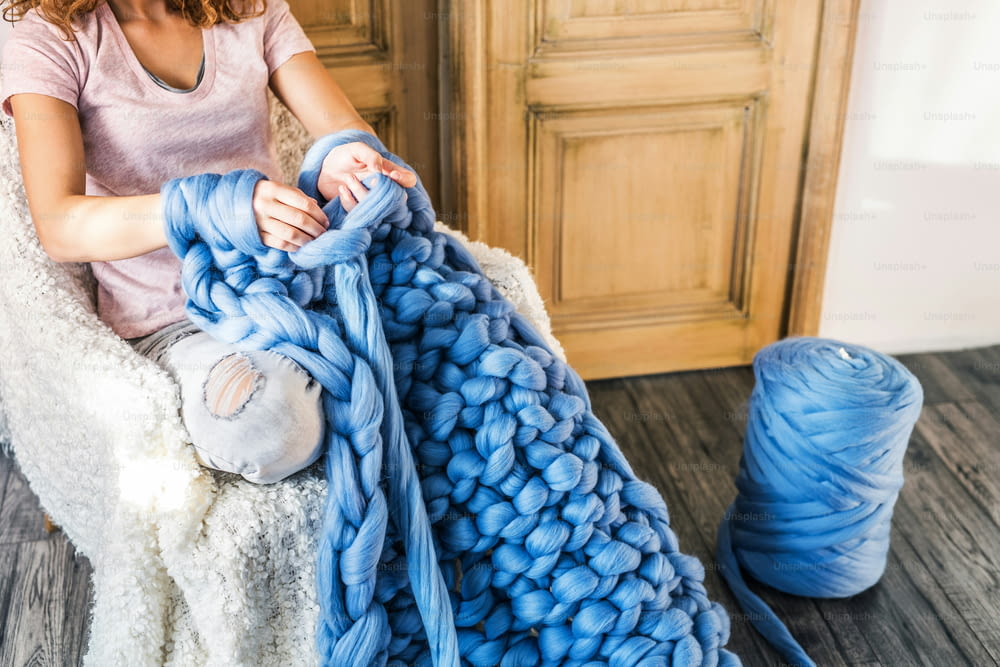 Petite entreprise d’une jeune femme. Femme méconnaissable tricotant à la main une couverture en laine.
