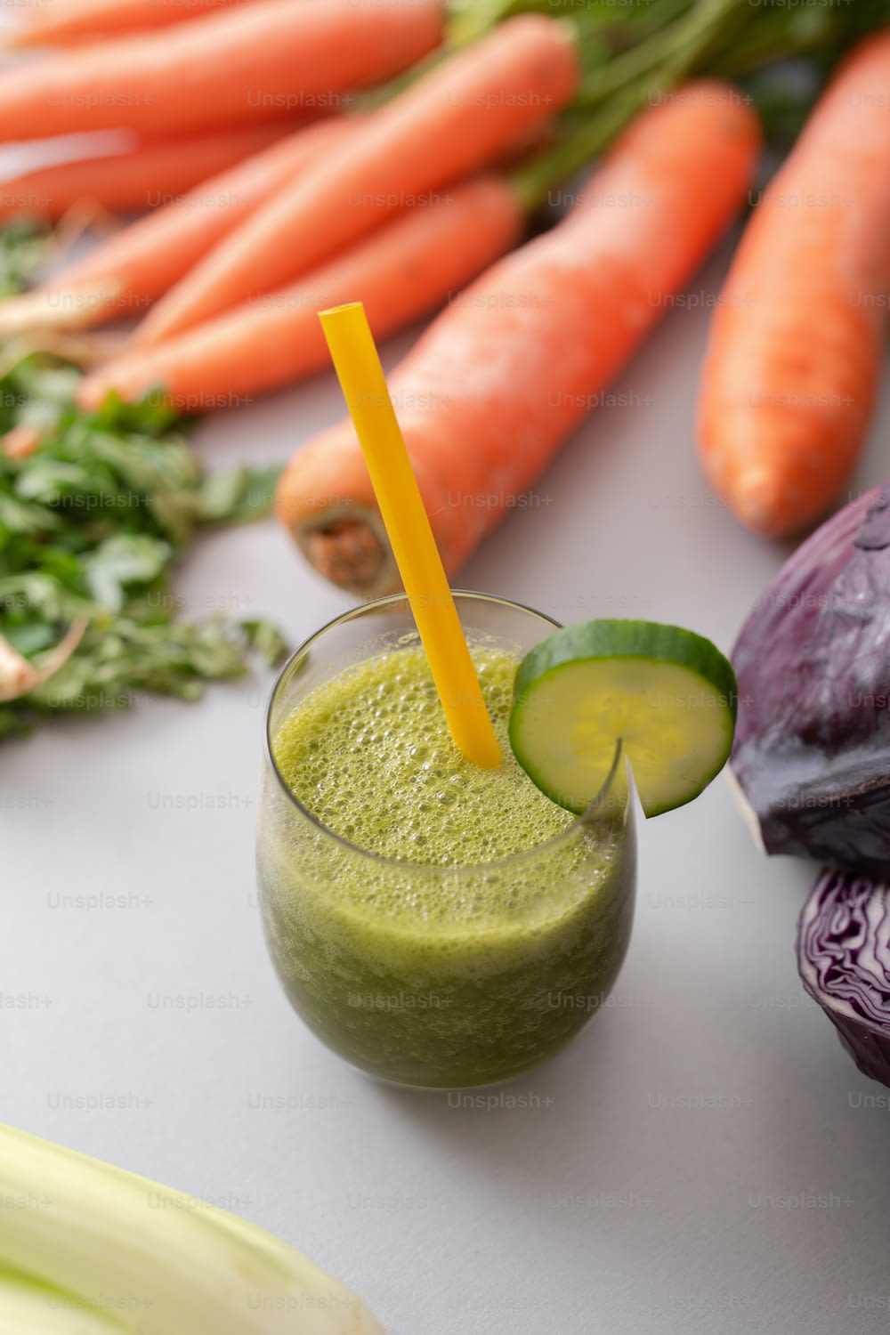 A green smoothie in glass with straw and cucumber and vegetagbles at background, detox, vegan, vegetarian healthy vegetable drink